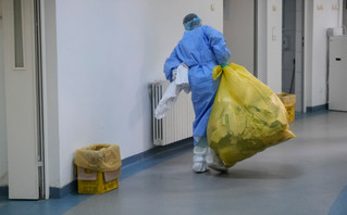 Υγειονομικός μεταφέρει σακούλα με απορρίμματα Υγειονομικός μεταφέρει σακούλα με απορρίμματα