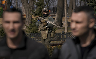 A Ukrainian serviceman guards the area as Kyiv Mayor Vitali Klitschko, right, speaks during a press conference next to his brother, former heavyweight boxing world champion Wladimir Klitschko, in Kyiv, Ukraine,Wednesday, March 23, 2022. From a public park in the city, Klitschko said 264 civilians had so far died from Russian bombardment on the capital, including four children. As he spoke to reporters, explosions and loud gunfire echoed across the city