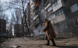Woman in front of destroyed houses in Mariupol