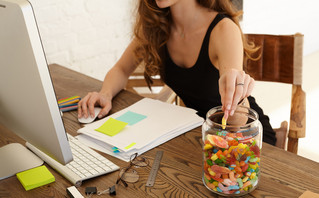 Γυναίκα τρώει γλυκά όσο δουλεύει