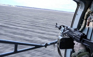 In this photo taken from video released by Russian Defense Ministry Press Service on Tuesday, March 1, 2022, a Russian soldier points a gun from a Russian military helicopter as it flies over an undisclosed location in Ukraine