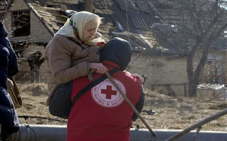 A Red Cross worker carries an elderly women during evacuation in Irpin, some 25 km (16 miles) northwest of Kyiv, Friday, March 11, 2022. Kyiv northwest suburbs such as Irpin and Bucha have been enduring Russian shellfire and bombardments for over a week prompting residents to leave their home