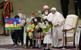 Pope Francis greets children refugees from Ukraine, during his weekly general audience in the Paul VI Hall, at the Vatican, Wednesday, April 6, 2022. Ukrainian script on the drawing reads "We want peace" 