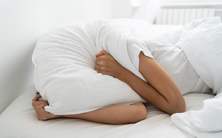 Γυναίκα σε κρεβάτι με το μαξιλάρι πάνω στο κεφάλι της
