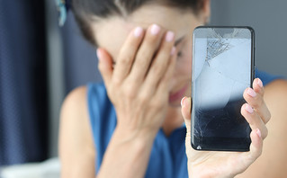 γυναίκα κρατάει το σπασμένο κινητό της