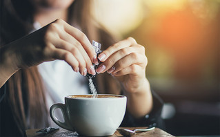 Γυναίκα βάζει ζάχαρη στον καφέ της