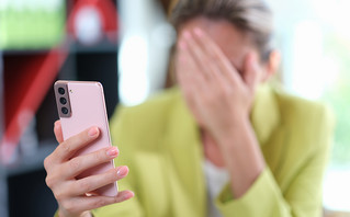 Στενοχωρημένη γυναίκα κρατάει το κινητό της