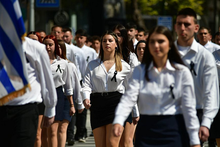 Λάρισα: Μαύρες κορδέλες, περιβραχιόνια και κονκάρδες με συνθήματα διαμαρτυρίας στην παρέλαση για την 25η Μαρτίου