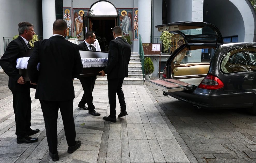 a group of men carrying a coffin in a hearse