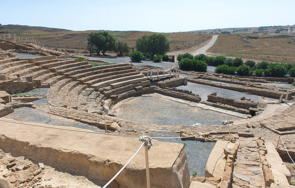 a stone amphitheater with a path and trees in the background