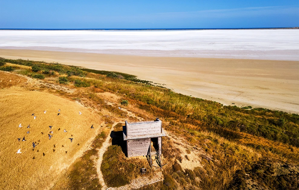 a small wooden structure on a hill with a large flat beach